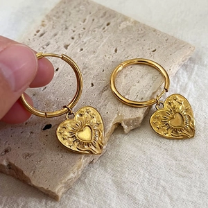 Boucles d'oreilles cœur vintage dorées avec pendentif étoile sur fond pierre minimaliste