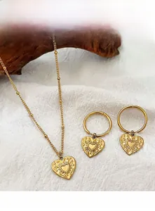 Detail view of retro gold heart jewelry set with engraved sunburst and star patterns