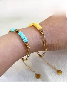 Detail of colorful seashell stone beads and gold paperclip link bracelets on wrist