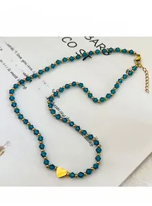 Vue macro d'un collier de perles bleues avec pendentif coeur doré sur fond blanc