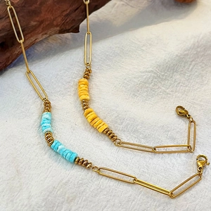 Golden paperclip chain bracelet with colorful beads on a natural linen background
