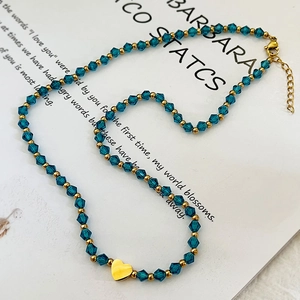 Collier de perles de cristal bleu avec un pendentif coeur doré sur fond stylé