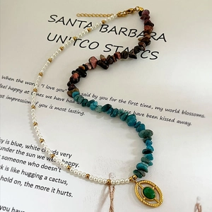 Asymmetric necklace with natural stones pearls and gold oval pendant on a book