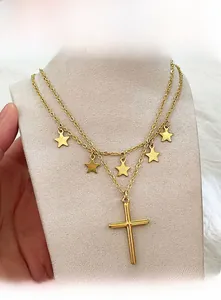 Close-up of double-layered gold necklace with five-pointed stars and cross pendant
