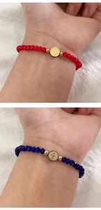 Gros plan de bracelets en perles rouges et bleues avec médailles Saint-Benoît dorées