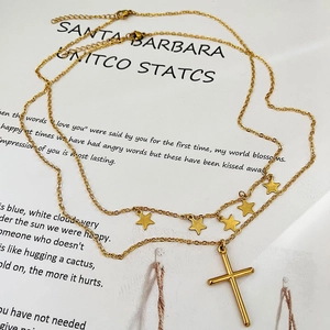 Double-layered gold star necklace with a minimalist cross pendant on white background