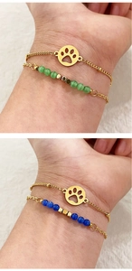 Detail of double-layer gold bracelets with opal cat paw charms and colored beads