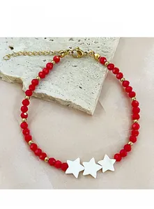Macro shot of red crystal beads and white shell stars on a handmade beaded bracelet