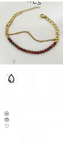 Detail of layered bohemian bracelet featuring rainbow beads and gold Figaro chain link