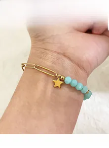 Detailed close-up of a vintage chain bracelet with light blue beads and a gold star charm