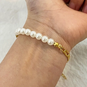 Bohemian stainless steel bracelet with white pearls and gold metal chain on wrist