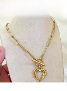 Dettaglio di una collana a graffetta dorata con pendente a cuore e chiusura a levetta