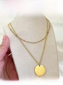 Detail of minimalist double-layered gold necklace with round pendant on a jewelry bust