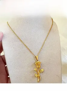 Détail d'un pendentif rose 3D doré avec pétales ciselés sur une fine chaîne maille forçat