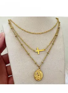 Close-up of a layered 18k gold-plated necklace with a cross and Virgin Mary medal pendant