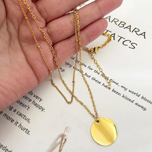 Minimalist double layer gold necklace featuring a round disc pendant and beaded chain
