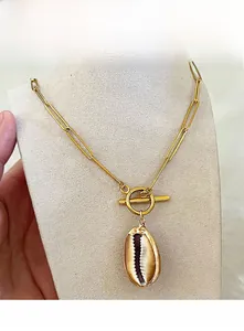 Dettaglio della collana boho a graffetta dorata con ciondolo a conchiglia e chiusura OT