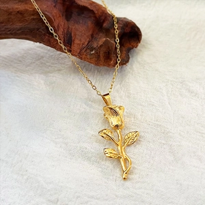 Collier vintage avec pendentif rose dorée en acier inoxydable sur support en bois sombre