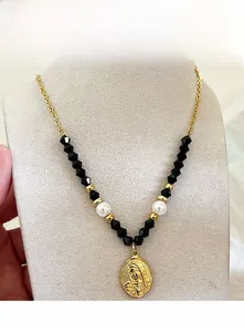 Dettaglio di una collana fatta a mano con perle nere e ciondolo di Maria