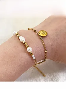 Détail d'un ensemble de bracelets perlés dorés avec perles et pendentif floral au poignet