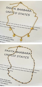 Détails de colliers dorés avec pendentifs étoiles et perles noires sur fond blanc épuré