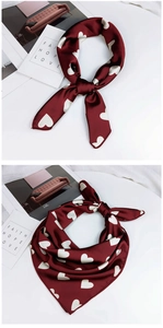 Détail d'un foulard en soie bordeaux avec imprimé cœur et texture satinée lisse
