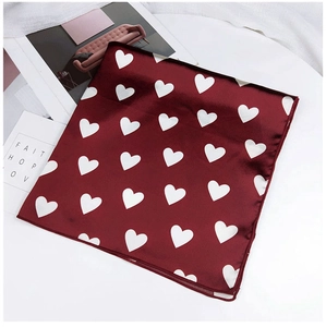 Gros plan d'un foulard en soie rouge à motifs de cœurs et texture satinée
