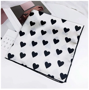 Gros plan d'un foulard en soie à imprimé cœur avec des finitions de couture noires