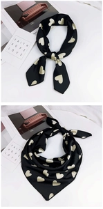 Détail d'un foulard soyeux avec motifs de cœurs dorés sur tissu satiné noir