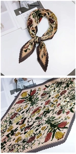 Détail d'un foulard plissé en soie champagne avec texture accordéon et imprimés floraux élégants