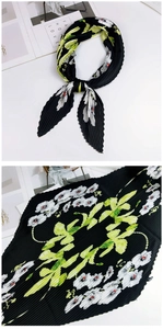 Vue détaillée d'un foulard plissé noir avec des motifs de petites fleurs et feuilles vertes