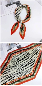 Détail d'un foulard en soie plissé aux motifs géométriques orange et vert