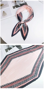 Détail du foulard plissé rose en losange avec bordures géométriques et texture soyeuse