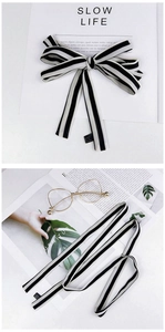 Detail of a black and white striped silk scarf tied in a bow on a stylish magazine