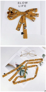 Close-up of yellow skinny scarf with white bird print in bow and flat layout views