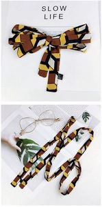 Detailed view of geometric cube pattern scarf styled with vintage accessories and magazine