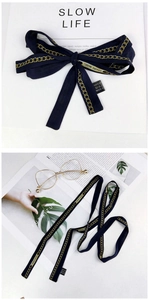 Detail of dark blue viscose scarf with gold chain pattern as a bow and bag accessory