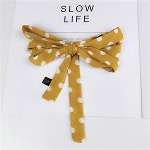 Retro yellow hair scarf with white polka dots and a large bow on a magazine background