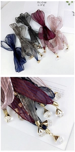 Close-up of sheer striped organza ribbons with golden caps and crystal pendants in multiple colors