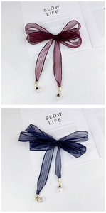 Detail of striped mesh bow hair accessory with crystal pendant in wine red and navy blue