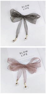 Detail of sheer striped ribbon hair bow with hanging faceted crystal bead charm