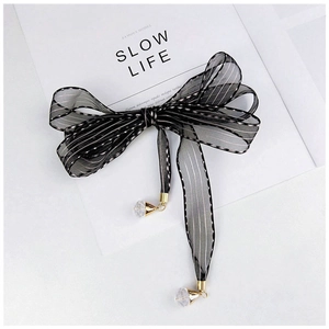 Detail of striped mesh bow accessory with crystal pendants and elegant metallic hardware