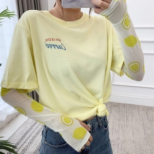 Detail of sun protection sleeves with lemon print paired with a yellow knotted t-shirt