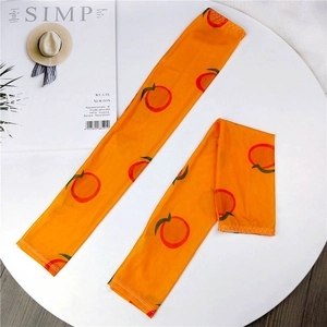 Detailed close-up of orange sun protection sleeves with cute fruit prints on fabric