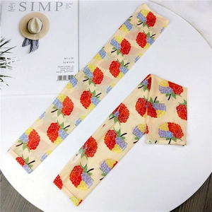Detail view of two chiffon arm sleeves with colorful berry print on a white table