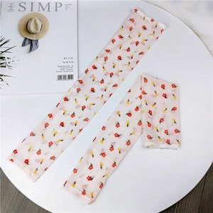 Flat lay of floral mesh arm sleeves for sun protection with magazine and hat props
