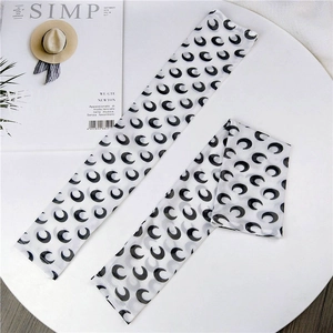 Detailed view of white mesh sun sleeves with crescent moon patterns on a white table