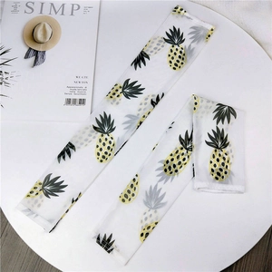 Detail of white mesh sun protection sleeves with yellow pineapple prints on a white stand