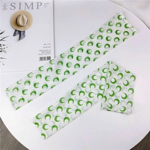 Detail of arm sleeves with green crescent moon patterns on light chiffon fabric