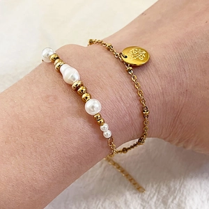 Bracelet double couche en perles et acier titane avec pendentif fleur dorée porté au poignet